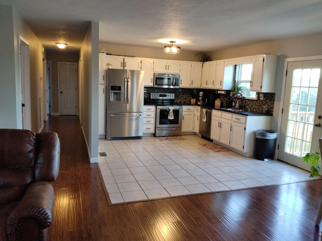 kitchen featuring white cabinetry, sink, stainless steel appliances, tasteful backsplash, and light tile patterned floors