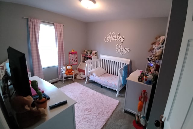 bedroom with dark colored carpet and a nursery area