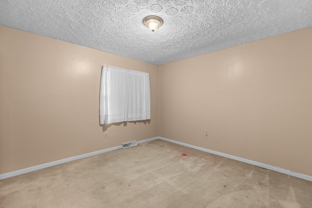 empty room with light carpet and a textured ceiling