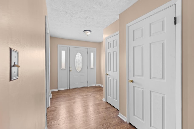 foyer entrance featuring a textured ceiling and light wood-type flooring