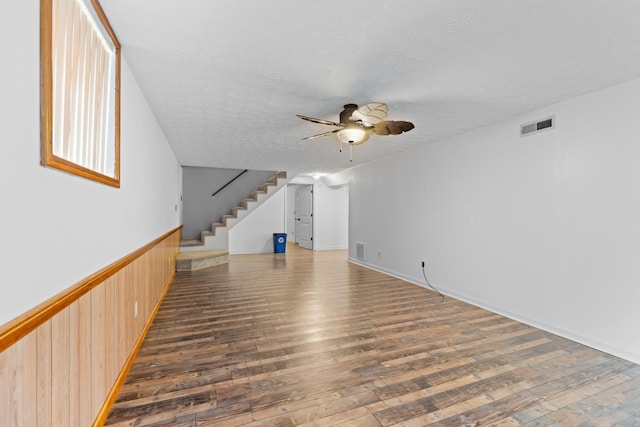 unfurnished living room featuring ceiling fan, dark hardwood / wood-style floors, and a textured ceiling