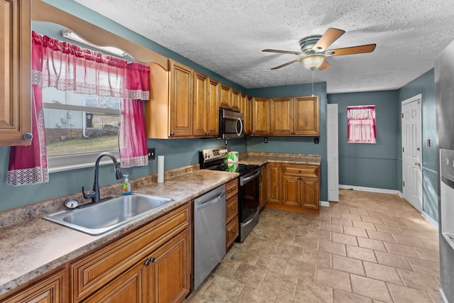 kitchen with ceiling fan, appliances with stainless steel finishes, sink, and a textured ceiling