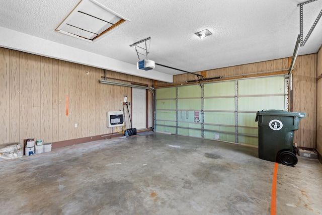 garage featuring a garage door opener, heating unit, and wood walls