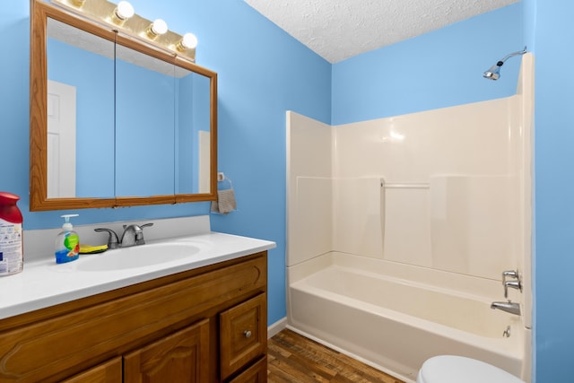 full bathroom featuring toilet,  shower combination, a textured ceiling, vanity, and hardwood / wood-style flooring