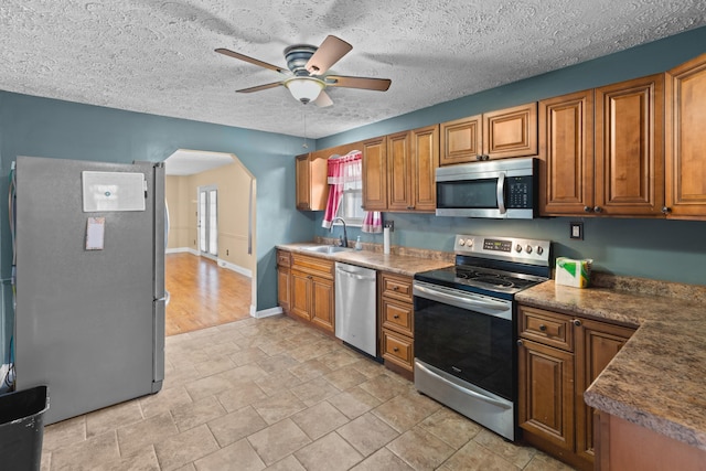 kitchen with sink, hanging light fixtures, a textured ceiling, appliances with stainless steel finishes, and ceiling fan