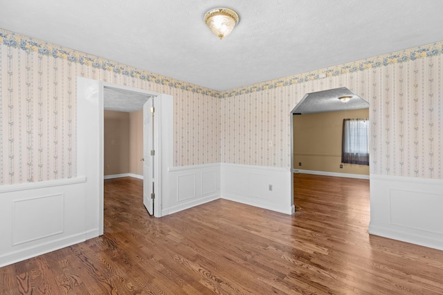 empty room with wood-type flooring and a textured ceiling