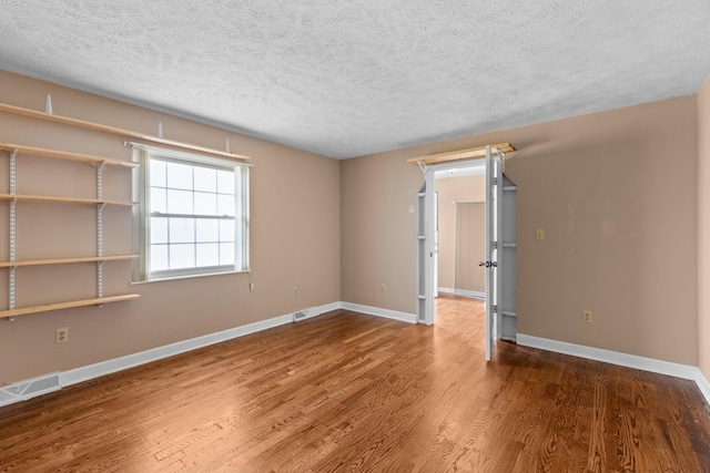 empty room with wood-type flooring and a textured ceiling