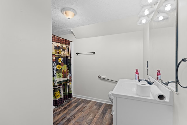 bathroom featuring vanity, wood-type flooring, toilet, and a textured ceiling