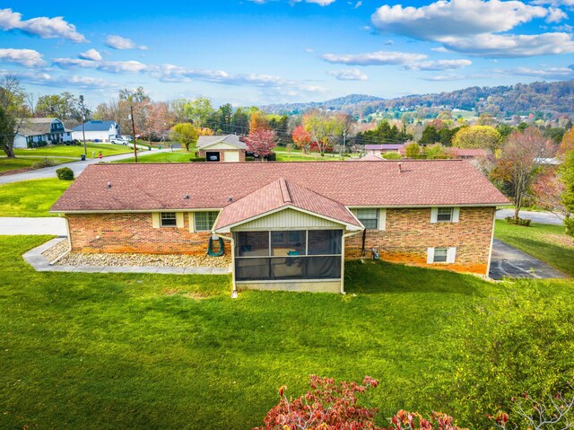 back of house featuring a yard, a mountain view, and a sunroom