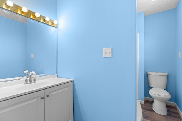 bathroom featuring vanity, a textured ceiling, wood-type flooring, and toilet