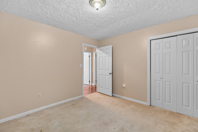 unfurnished bedroom with light colored carpet, a closet, and a textured ceiling