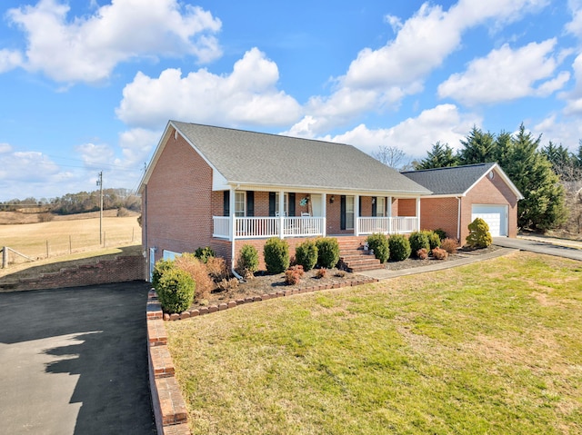 view of front of home with covered porch, driveway, a front lawn, and brick siding