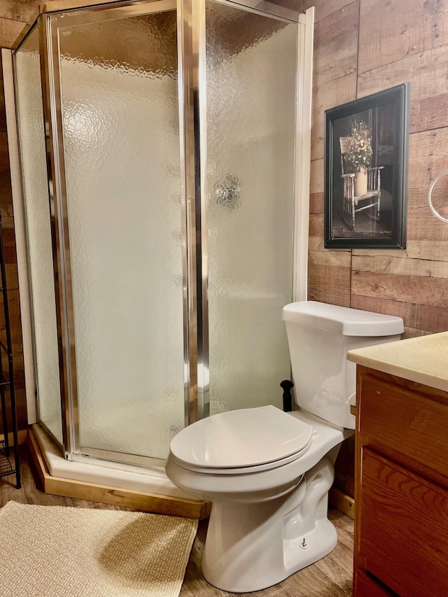 bathroom with vanity, a shower with door, hardwood / wood-style flooring, toilet, and wood walls