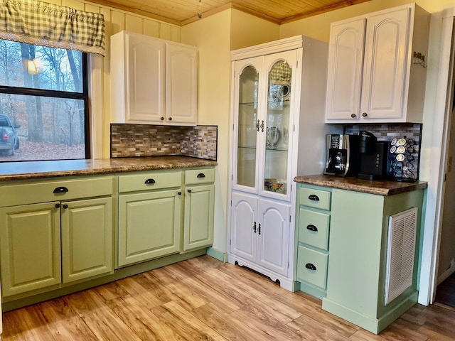 kitchen featuring decorative backsplash, ornamental molding, light hardwood / wood-style flooring, wooden ceiling, and white cabinetry