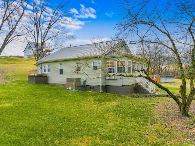 rear view of property with a lawn and central air condition unit