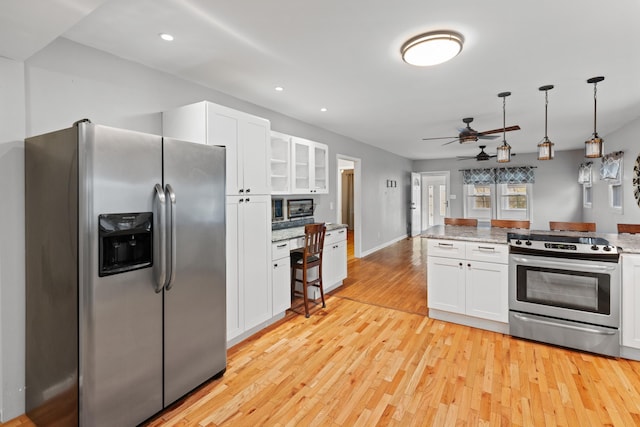 kitchen with decorative light fixtures, light stone countertops, white cabinets, and appliances with stainless steel finishes