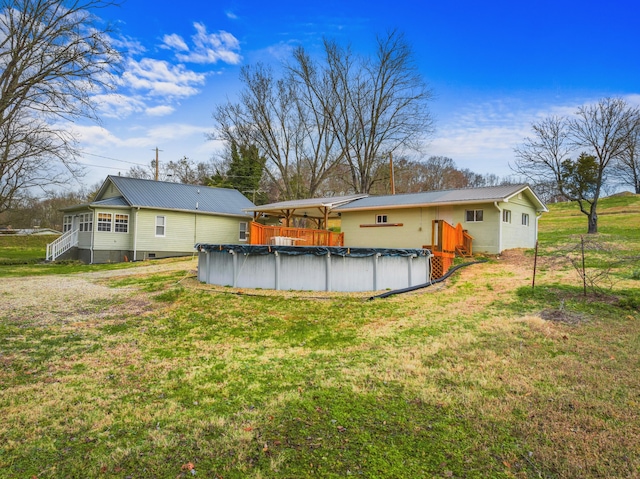 rear view of property featuring a covered pool and a yard