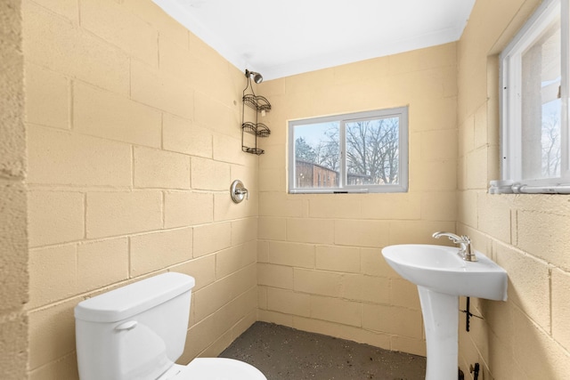 bathroom with concrete flooring, tiled shower, and toilet