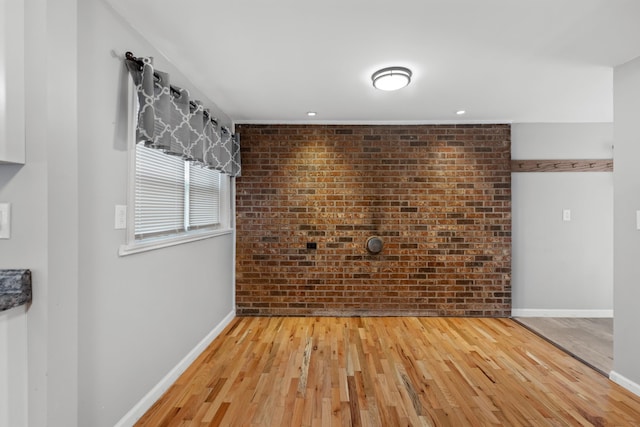 spare room with hardwood / wood-style flooring and brick wall