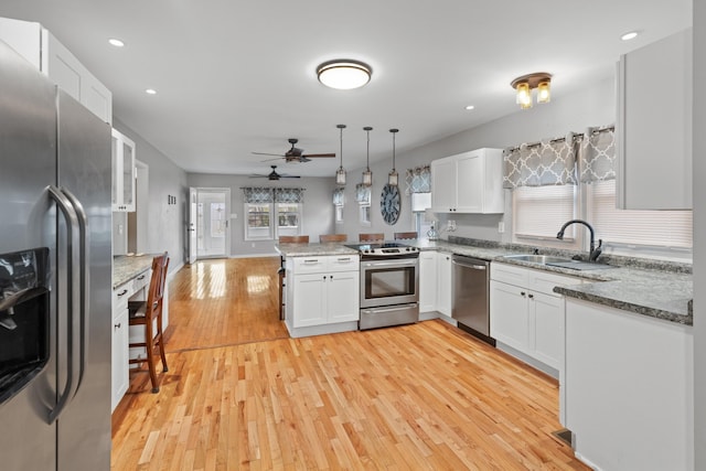 kitchen with decorative light fixtures, white cabinetry, sink, kitchen peninsula, and stainless steel appliances