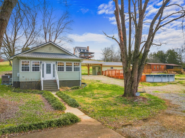 view of front of property featuring cooling unit, a covered pool, and a front yard