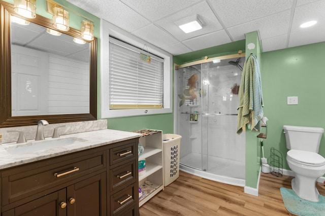 bathroom featuring a shower stall, toilet, wood finished floors, and a paneled ceiling
