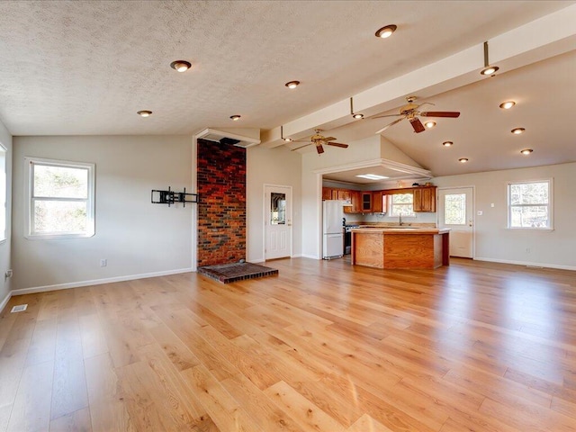 unfurnished living room with light hardwood / wood-style flooring, vaulted ceiling, a healthy amount of sunlight, and sink