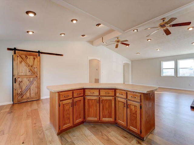 kitchen with vaulted ceiling with beams, a barn door, a kitchen island, and light hardwood / wood-style floors