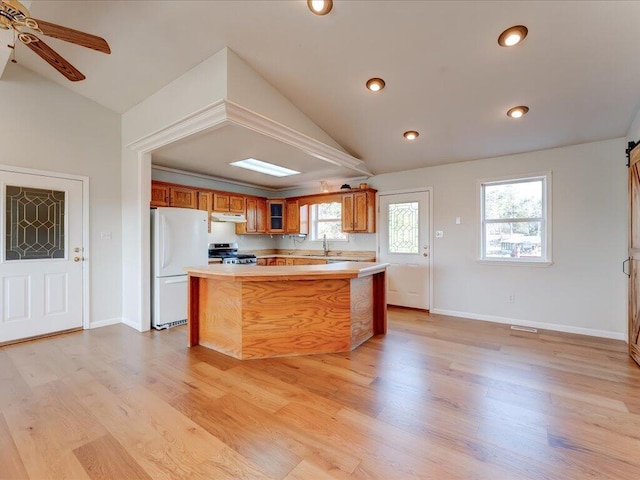 kitchen featuring sink, stainless steel range oven, white refrigerator, light hardwood / wood-style floors, and lofted ceiling