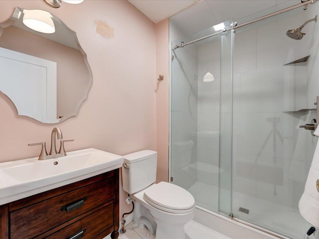 bathroom with a shower with door, vanity, and toilet