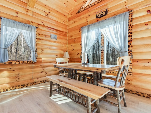 dining room featuring a healthy amount of sunlight, hardwood / wood-style floors, and log walls