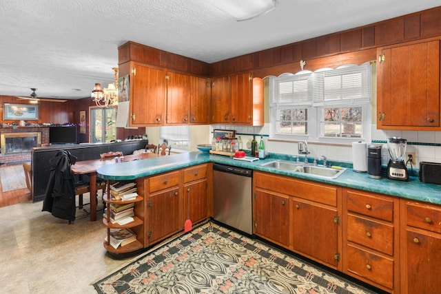 kitchen featuring kitchen peninsula, stainless steel dishwasher, sink, a fireplace, and a textured ceiling