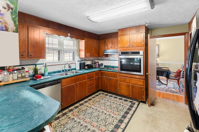 kitchen with sink, backsplash, a textured ceiling, and appliances with stainless steel finishes