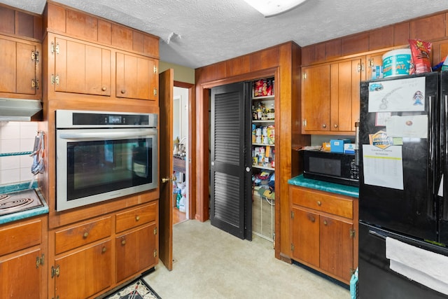 kitchen featuring black appliances, light carpet, and a textured ceiling