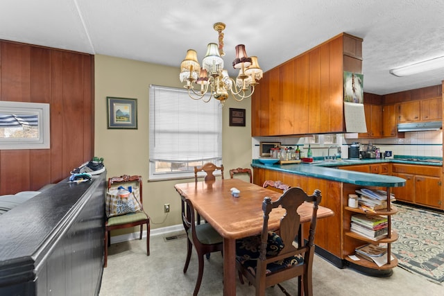 kitchen featuring sink, tasteful backsplash, a textured ceiling, stovetop, and a chandelier