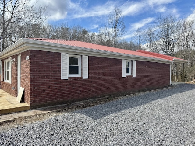 view of home's exterior with metal roof, brick siding, and driveway