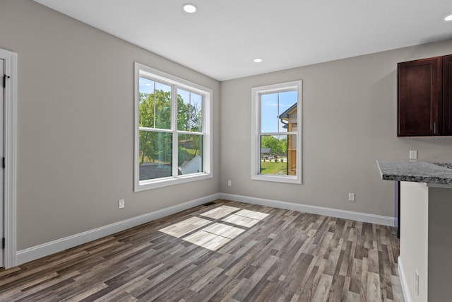 unfurnished dining area with baseboards, recessed lighting, and wood finished floors