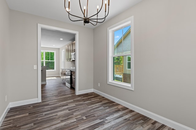 unfurnished dining area with baseboards, dark wood-style flooring, and a notable chandelier