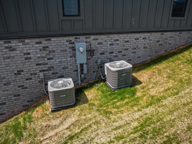 exterior details with brick siding, board and batten siding, and central air condition unit