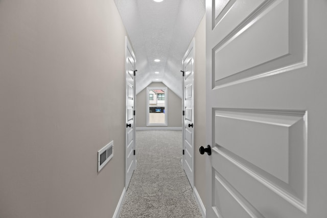 hall with carpet floors, baseboards, recessed lighting, a textured ceiling, and vaulted ceiling