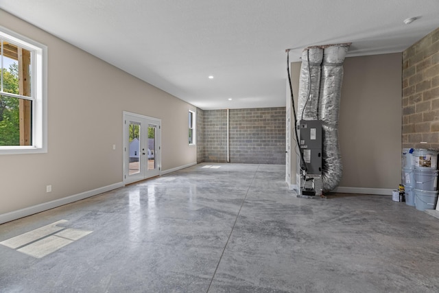 unfurnished living room featuring french doors, finished concrete flooring, baseboards, heating unit, and recessed lighting
