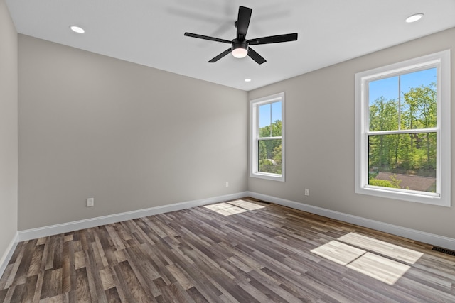 unfurnished room featuring baseboards, a ceiling fan, dark wood finished floors, and visible vents