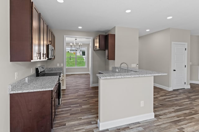 kitchen featuring wood finished floors, baseboards, an inviting chandelier, stainless steel appliances, and recessed lighting