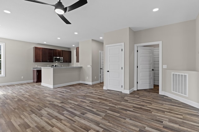 unfurnished living room featuring visible vents, a ceiling fan, baseboards, and wood finished floors