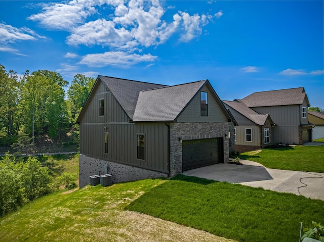 view of front of home featuring a garage, stone siding, a front yard, roof with shingles, and concrete driveway