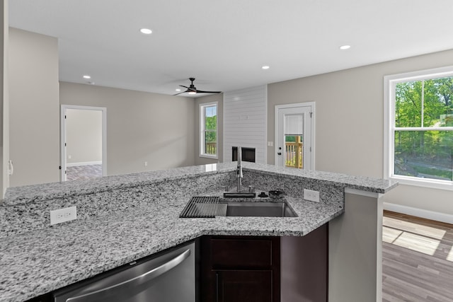 kitchen featuring a sink, a fireplace, dishwasher, a ceiling fan, and recessed lighting