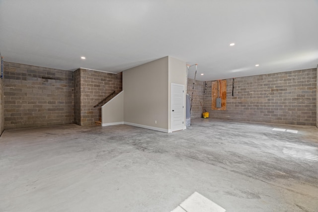 below grade area with concrete block wall, recessed lighting, and stairway