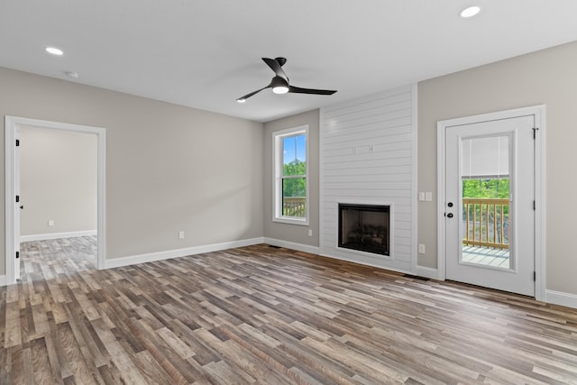 unfurnished living room with wood finished floors, baseboards, recessed lighting, a large fireplace, and a ceiling fan