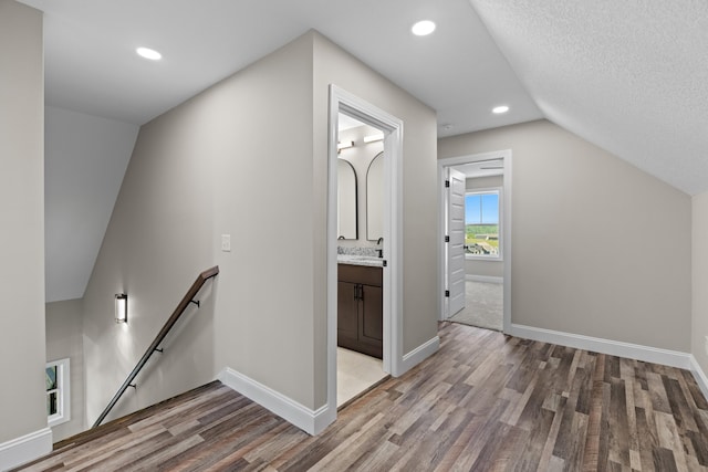 additional living space featuring a sink, light wood-style flooring, recessed lighting, baseboards, and vaulted ceiling