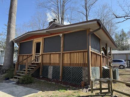 view of side of property featuring a sunroom, a chimney, and stairs